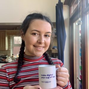 Photo of Belfast marketing trainee Maya McCloskey smiling holding a Make it Click mug